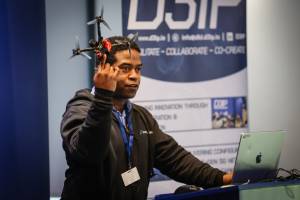 A speaker holding up a drone at D3IP's Autonomy Unleashed expo.
